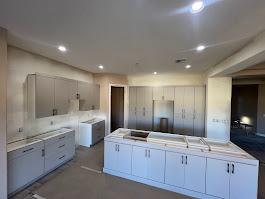 A kitchen under construction with a large center island, white cabinets, and a marble-look countertop. Kitchen Renovation
