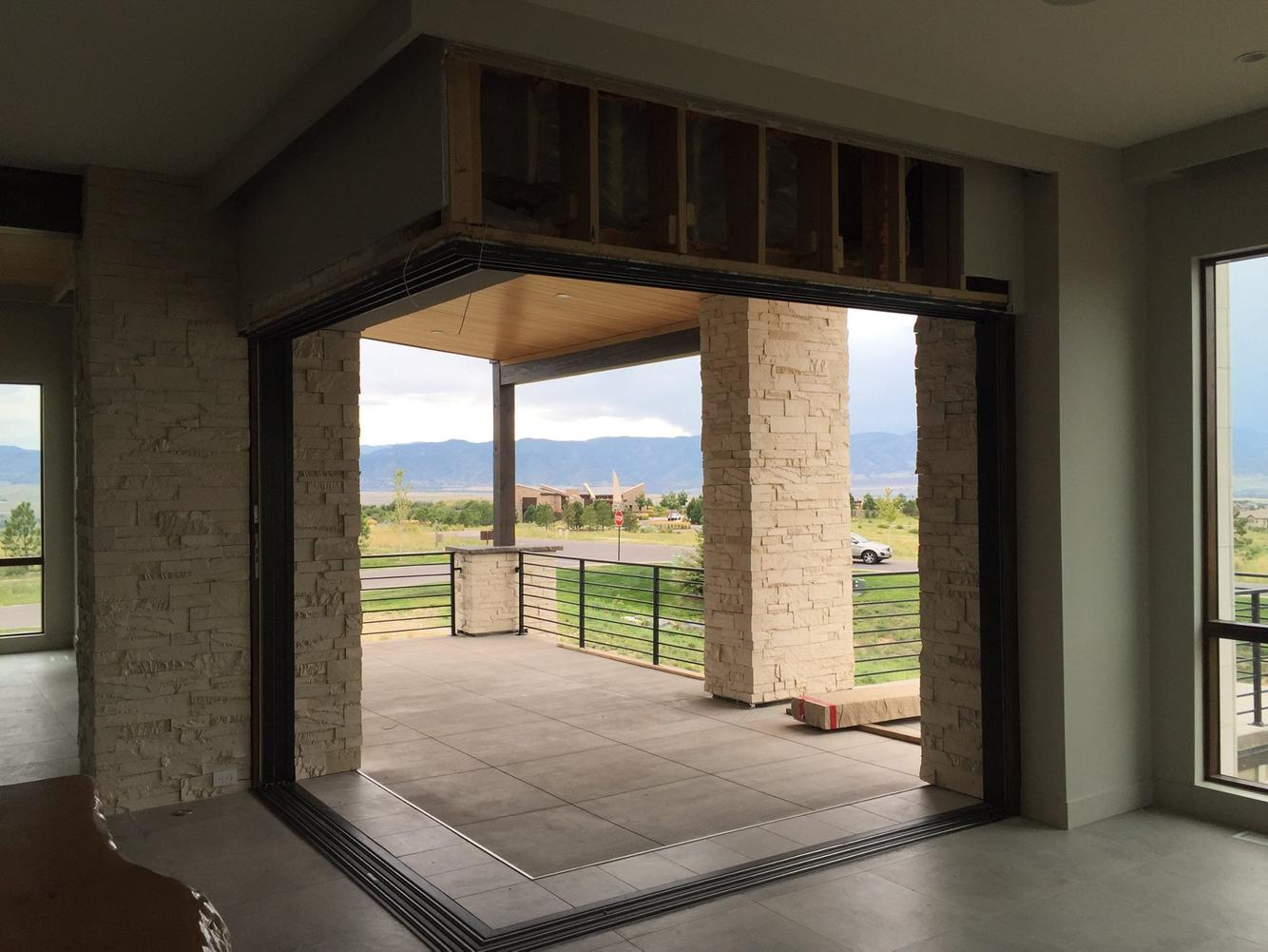New home construction with large bifold doors, a stone accent wall, and a view of the mountains.
