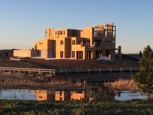 A wide-angle shot of a custom residential construction site in Southern Utah, showcasing the complete timber "skeleton" of a new home. The image highlights the intricate roof trusses, wall studs, and floor joists set against a backdrop of iconic red rock formations and a clear desert sky. New home wood framing Southern Utah desert