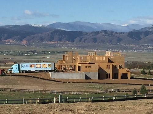 Exterior view of a large-scale residential house framing project under construction in the Southern Utah desert, highlighting the structural timber skeleton and red mountain backdrop. Custom home wood framing project Utah