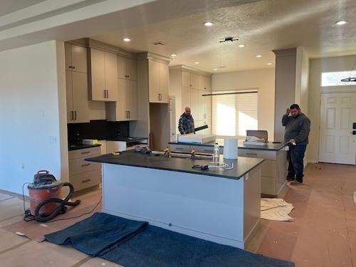 Luxury kitchen cabinetry with sleek black handles and dark stone surfaces in a residential remodel. Custom Taupe Kitchen Cabinets