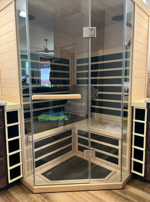 A modern infrared sauna with light wood siding, a glass door, and black interior panels. Custom-Built Infrared Sauna