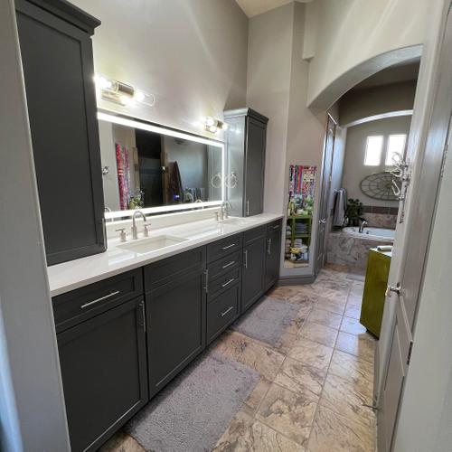 A modern bathroom remodel in St. George, Utah, with dark gray custom cabinetry, a lighted mirror, and a tile floor. Bathroom Remodel
