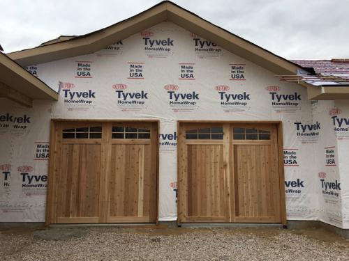 New home construction with custom wood garage doors and a Tyvek wrap exterior. Custom Barn Doors