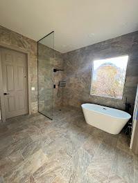 A modern bathroom with a freestanding soaking tub, glass shower enclosure, and large format tile flooring. Bathroom Renovation
