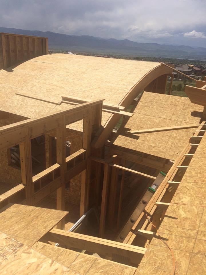 New home construction roof with a custom arched wood truss and a flat roof section. Whole House Framing Project