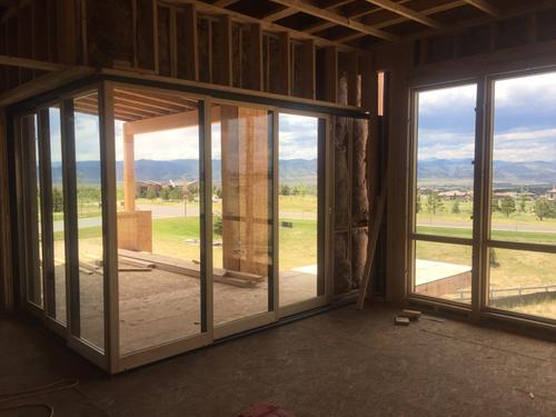 Construction site photo showing the industrial framing for a large multi-slide glass door system. The image highlights the heavy-duty structural header and precise floor track preparation in a new residential build in St. George, Utah. Large multi-slide door frame installation