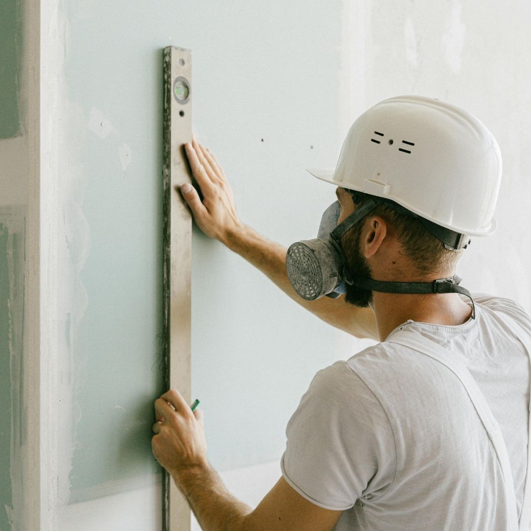 A man wearing PPE working on drywall