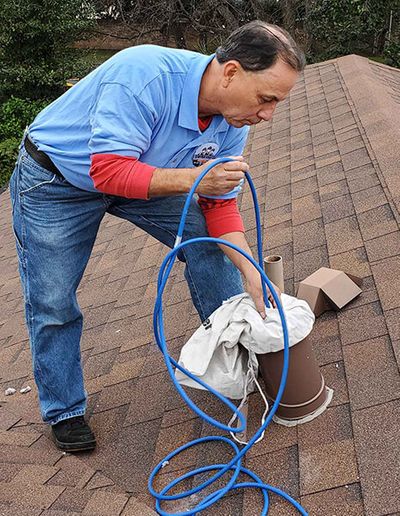 Man on roof cleaning out dryer vent