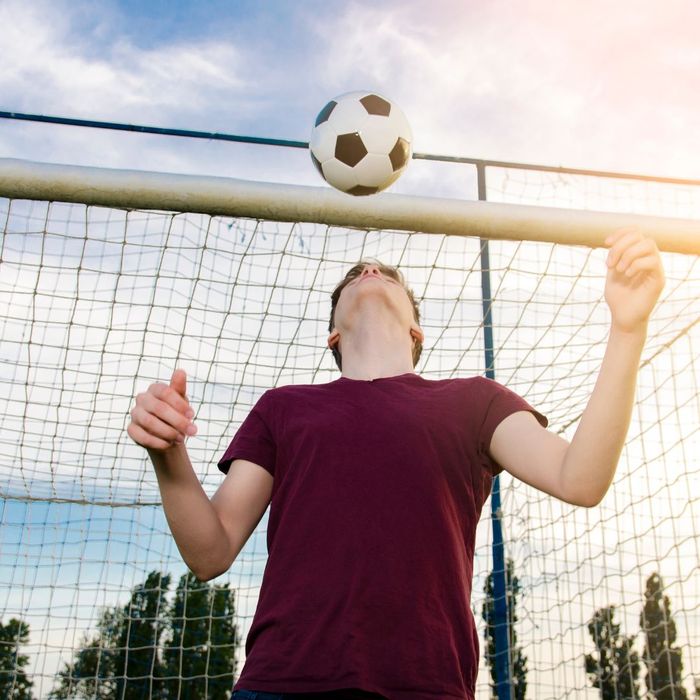A teen soccer player bounces the ball on his head