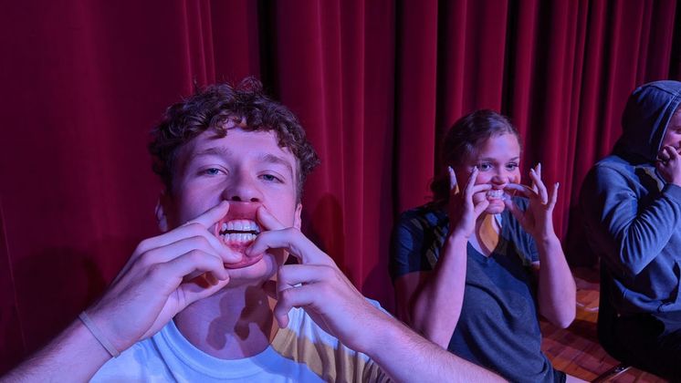 image of three people pulling their lips back and smiling