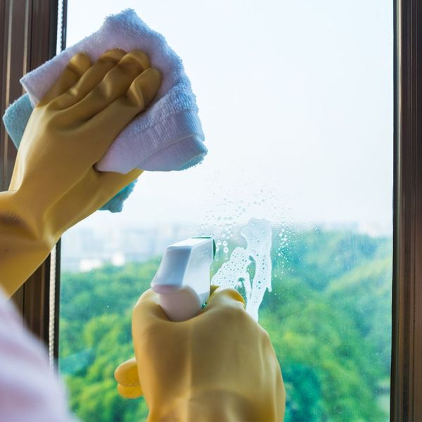 closeup of home window cleaning with yellow rubber gloves