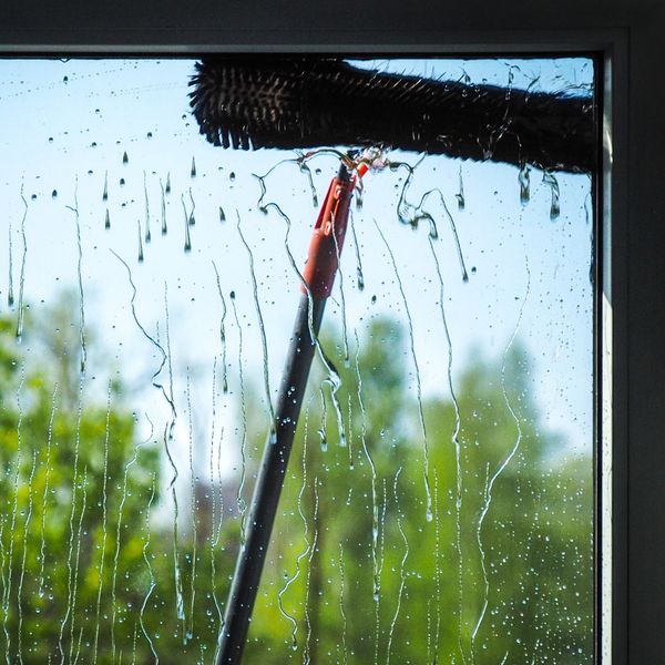 using an extended brush to clean a home exterior window