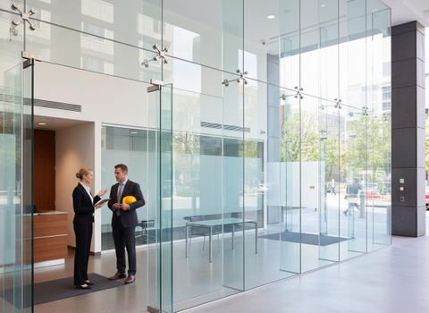 Business professionals discussing plans in modern glass lobby