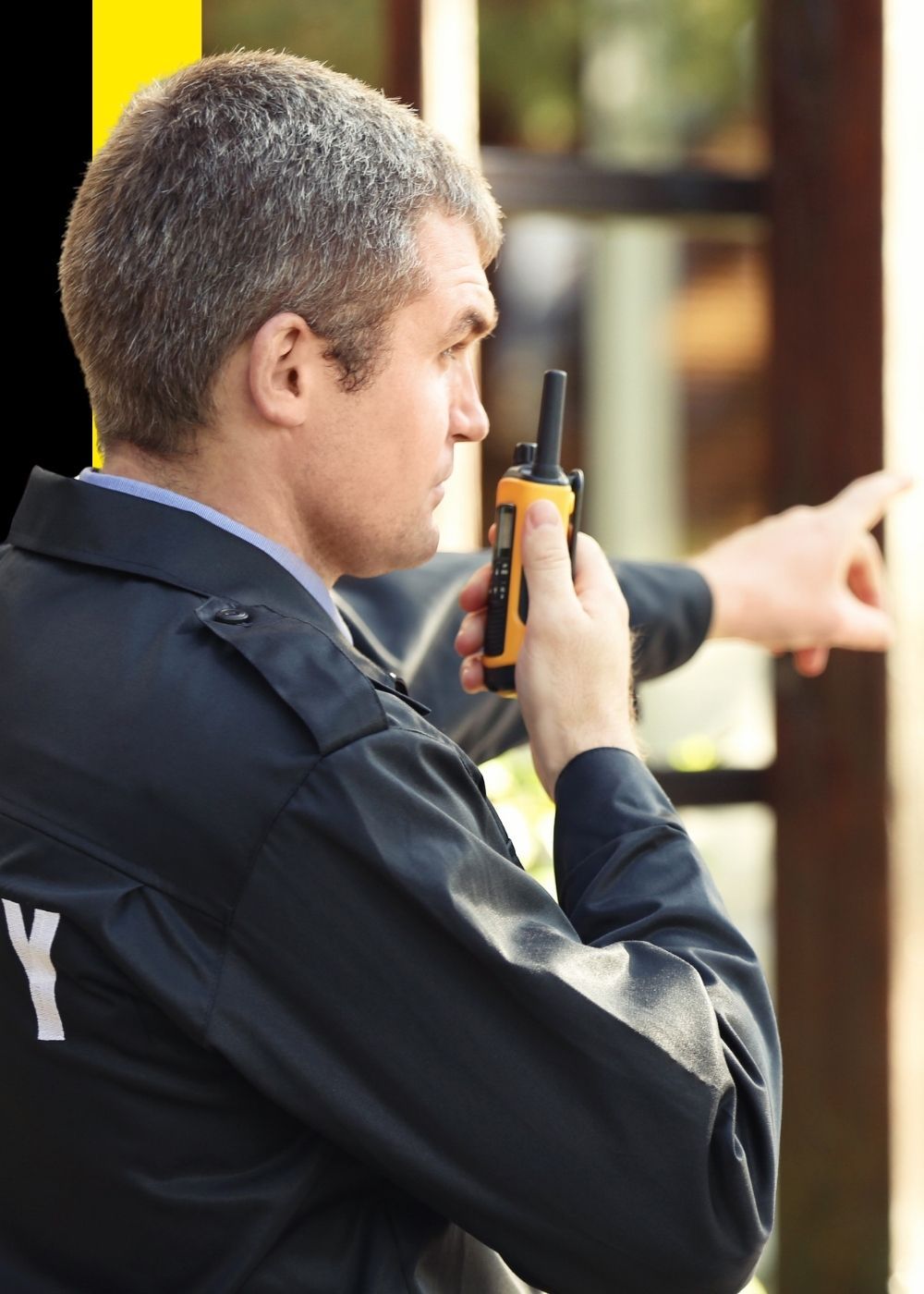 a security guard pointing while speaking into a radio