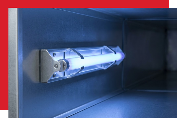 Photograph looking inside a residential metal duct, where a professionally installed UV germicidal light emits a cool blue-violet glow, sterilizing the airstream as it passes through the HVAC system.