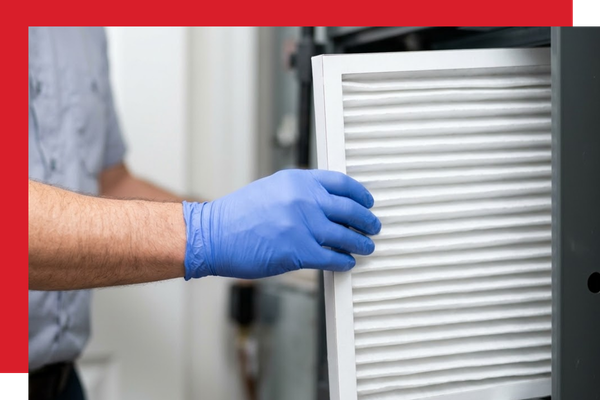 Photo focusing on an HVAC expert's gloved hand precisely sliding a pristine, white high-efficiency pleated media filter into a residential furnace slot, illustrating advanced air filtration.