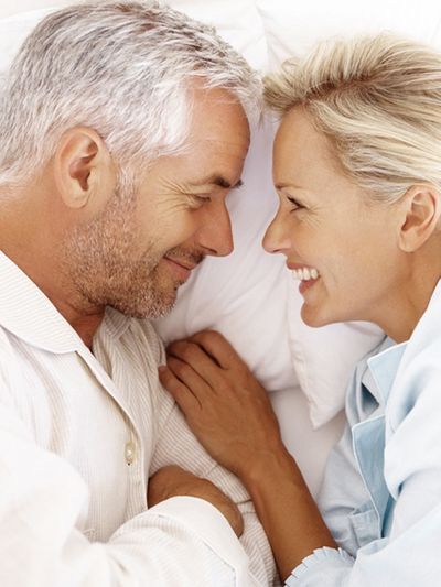 Mature couple smiling at each other in a bed
