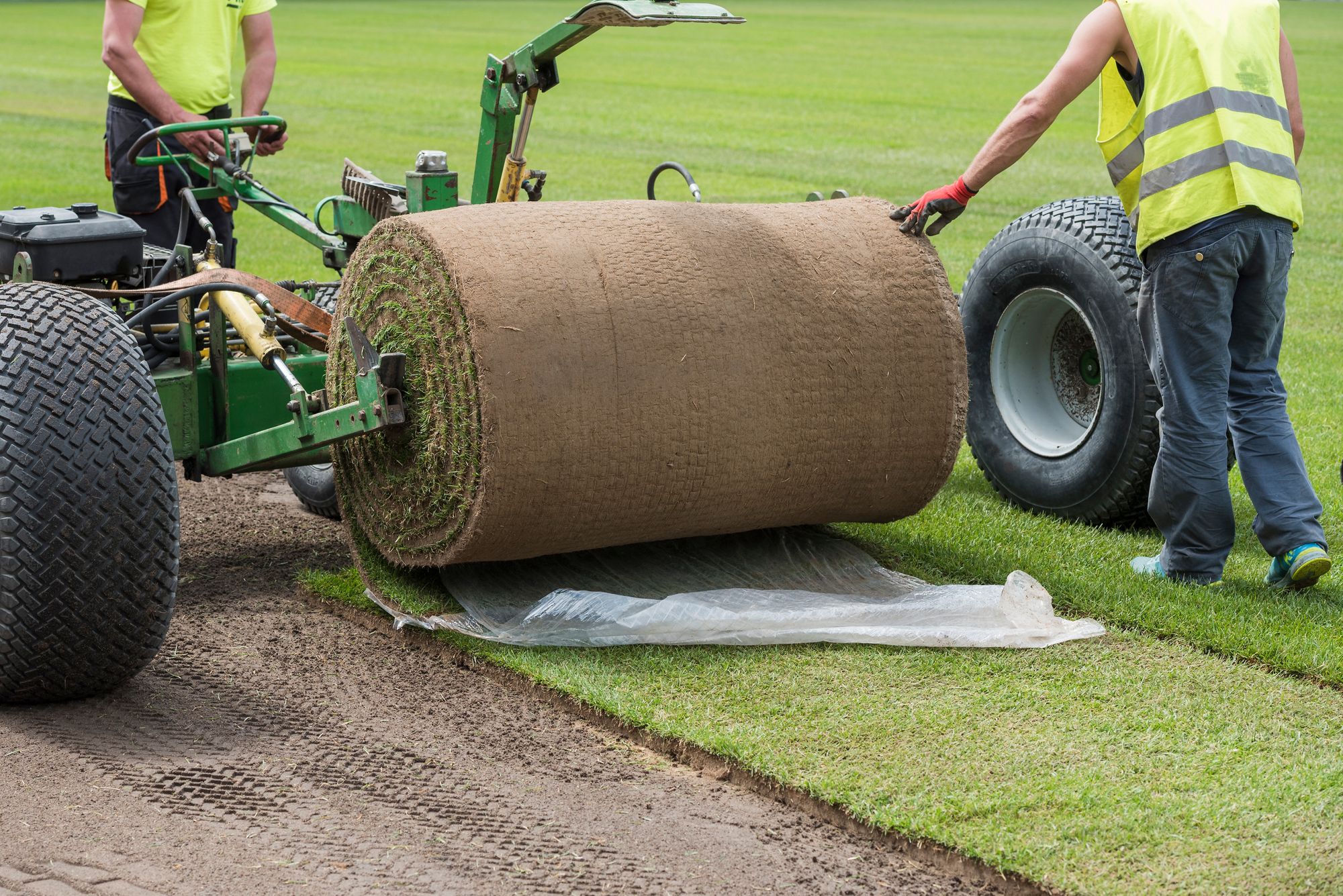 MEN ROLLING OUT LARGE ROLL OF SOD.jpg