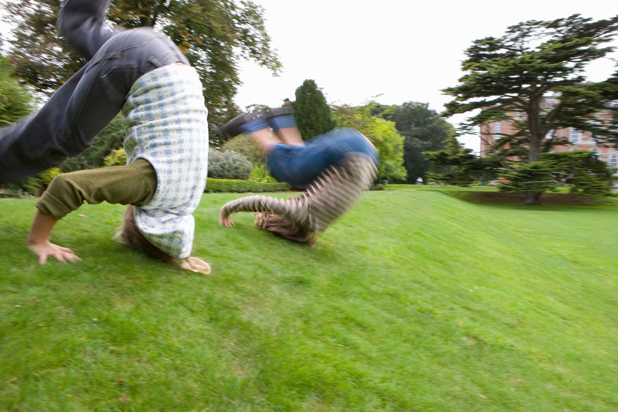 2 kids forward roll down a grassy slope.jpg
