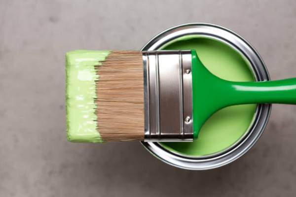 green paintbrush on top of a can of paint. 