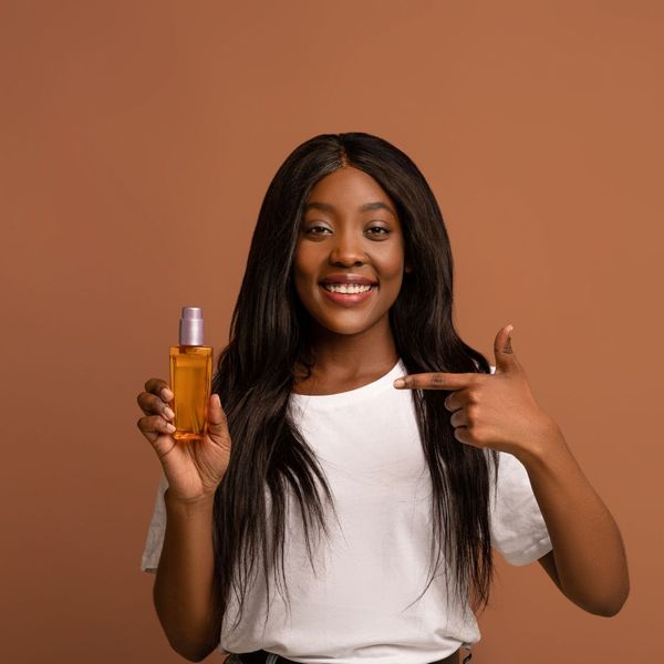 Black woman pointing to hair oil Black woman pointing to hair oil