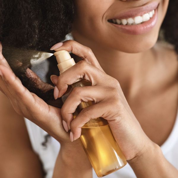 a woman sprays detangler in her hair a woman sprays detangler in her hair