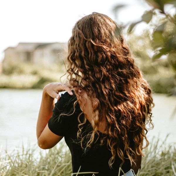 Woman with curly hair standing in a grass field