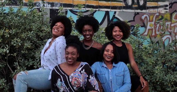 Photo of five women with natural hair sitting outside by Leighann Blackwood on Unsplash