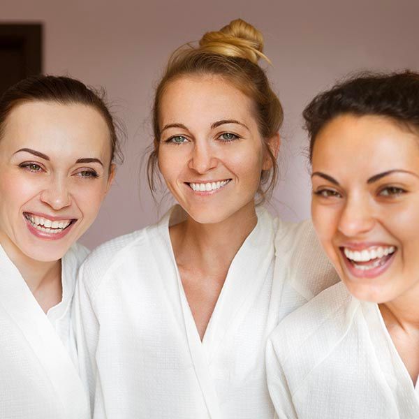 3 happy women wearing white robes