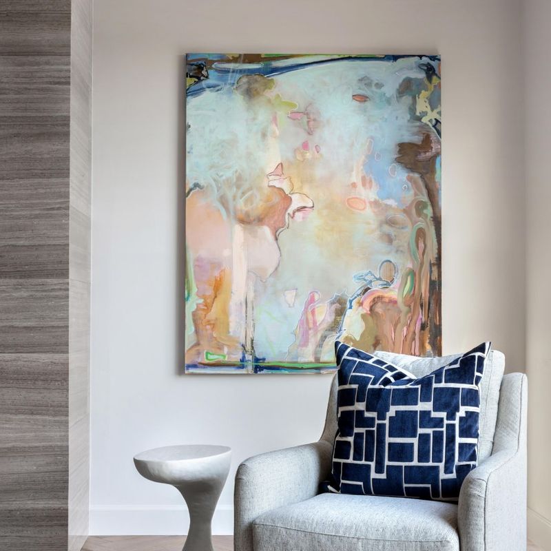 Abstract art piece on a wall behind a chair and side table. 