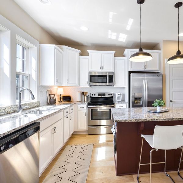 A bright and clean kitchen with white cabinets, a large island, and stainless steel appliances. A bright and clean kitchen with white cabinets, a large island, and stainless steel appliances.