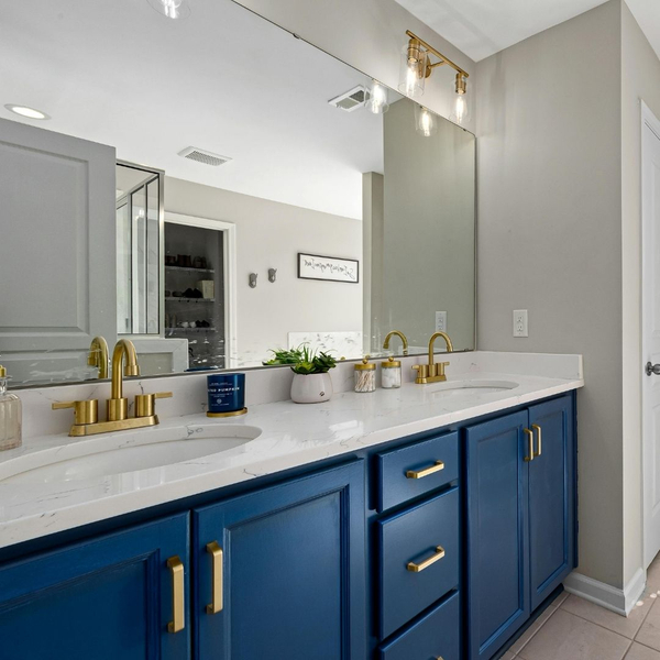 A clean and modern bathroom with a blue dual-sink vanity and a large mirror.