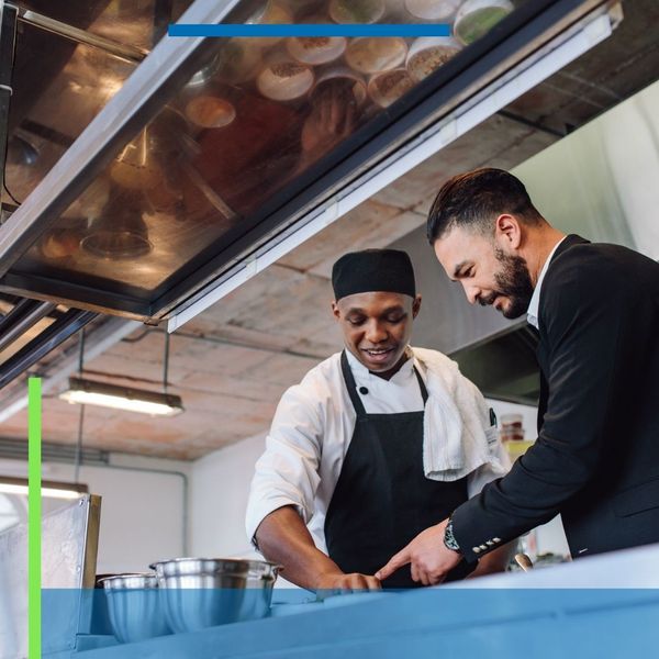 restaurant owner looks over operations in kitchen with chef