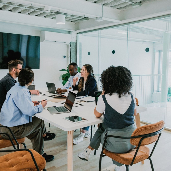 A diverse team of colleagues collaborates around a table in a bright, modern office.