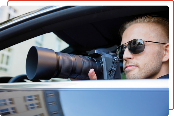 a private investigator using a camera in the car
