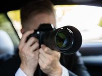 a private investigator using a camera in the car