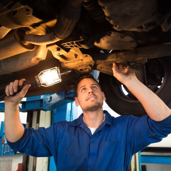 body shop technician examining underside of car