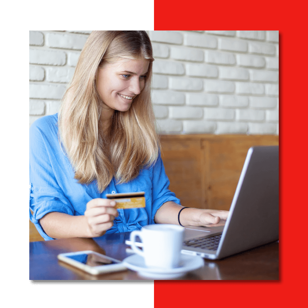 a happy woman using a credit card and a laptop