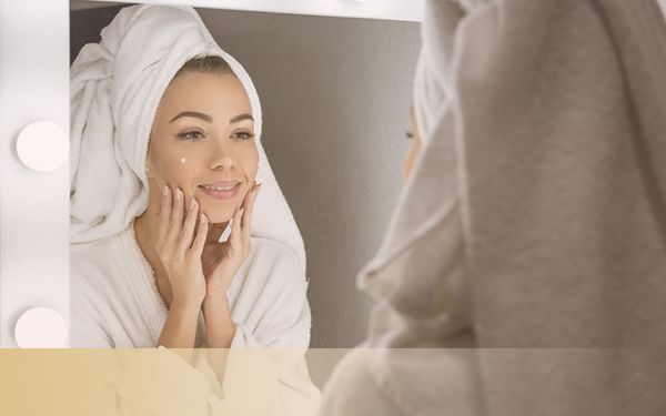 woman in bath towel looking at herself in a mirror
