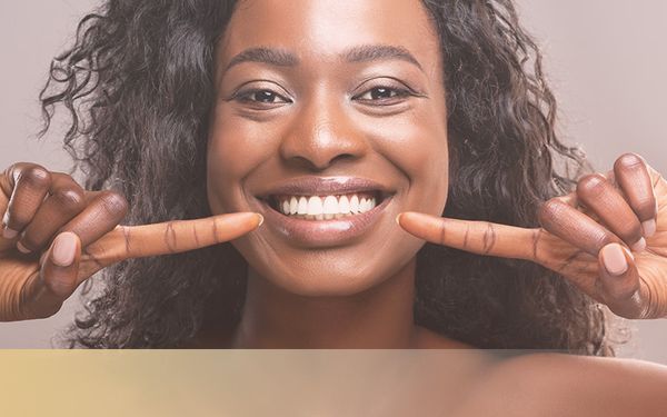 Black woman smiling and pointing to her teeth