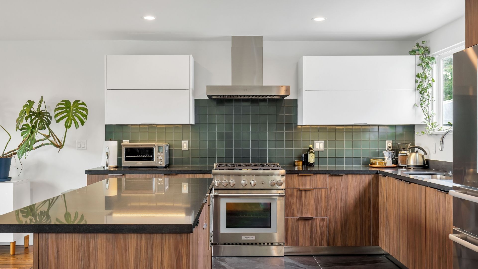 remodeled kitchen with dark countertops and green tile