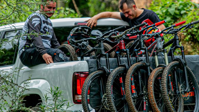 two people sitting in truck bed loaded with five mountain bikes
