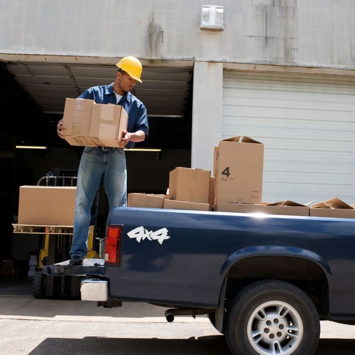 man in hard hat loading truck bed with boxes
