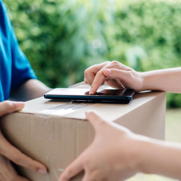 person typing on phone while handing off package