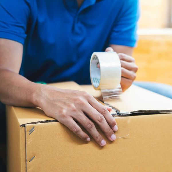 man using packing tape on package