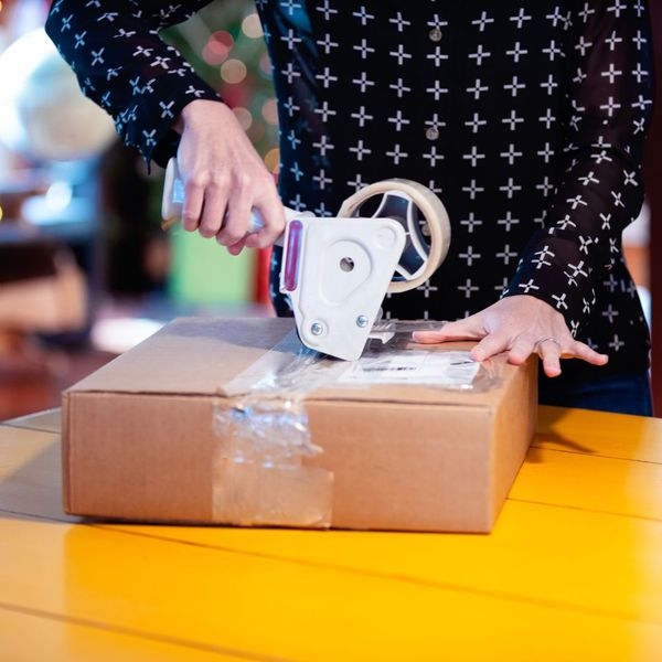 person taping a box to ship