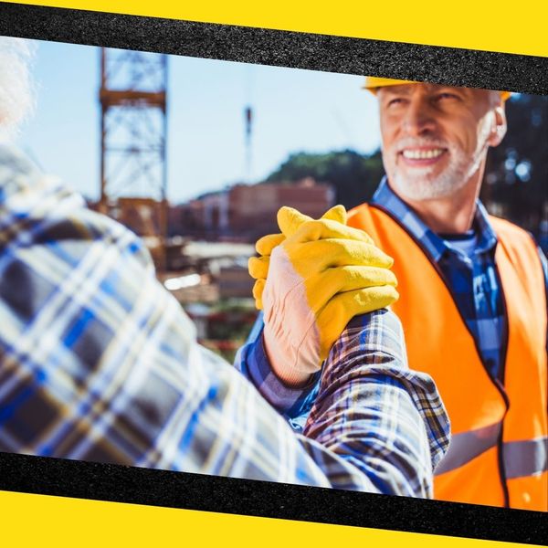 Two contractors smiling and shaking hands