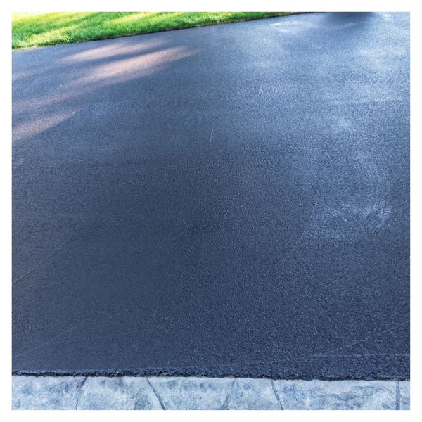 Smooth, newly sealed asphalt driveway with lawn.