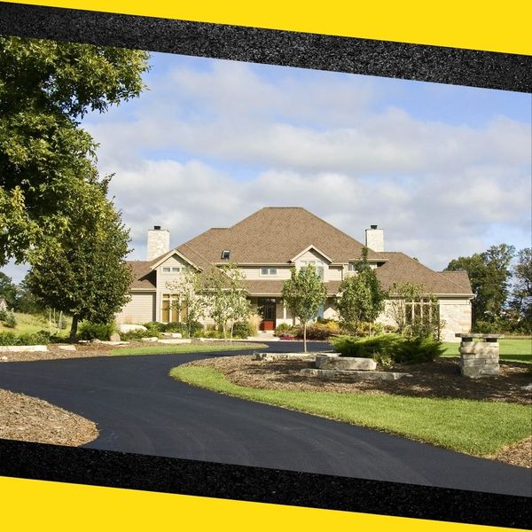 A freshly paved asphalt driveway leading to a nice house